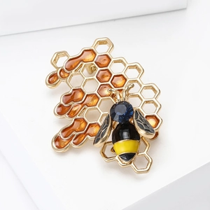 Detailed macro shot of an enamel bee and honeycomb brooch with amber resin and gemstones