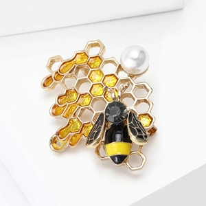 Macro detail of enamel honeybee brooch featuring honeycomb structure and faux pearl inlay