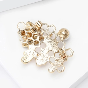 Close-up of golden honeycomb brooch back showing pin clasp and white pearl detail