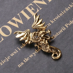 Detailed close-up of a vintage bronze dragon pendant showing scales and wing textures