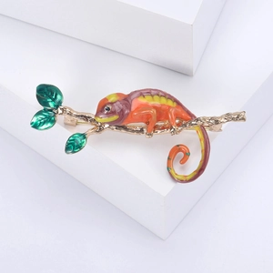 Détail de la broche caméléon en émail coloré aux tons orange et vert sur branche dorée
