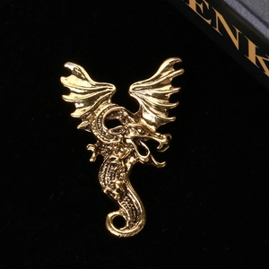 Detailed view of the gold dragon brooch with intricate scales on a black background