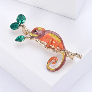 Vue détaillée de la broche caméléon en émail coloré sur une branche dorée élégante