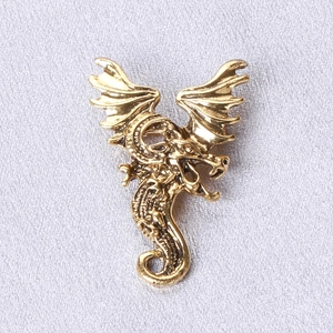 Macro view of vintage gold dragon brooch showing detailed scales and wing textures
