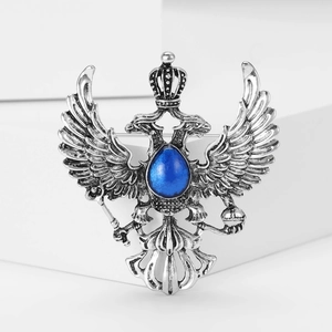 Macro detail of vintage alloy double-headed dragon brooch with blue teardrop gemstone