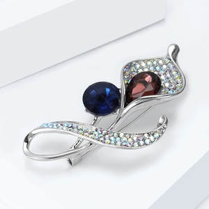 Macro view of crystal orchid brooch with deep blue round stone and purple drop gem