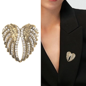 Spilla vintage ali d'angelo dorate con strass su blazer nero e sfondo bianco neutro