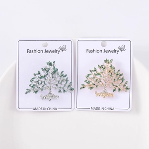 Détail de broches arbre de vie avec feuilles en émail vert et cristaux sur présentoir