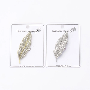 Detailed close-up of gold and silver feather brooches with micro-pave sparkling crystals