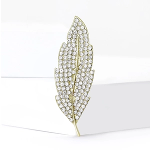 Elegant gold leaf brooch with white crystals on a white geometric display stand