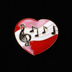 Broche cœur en émail rouge avec notes de musique dorées sur fond velours noir