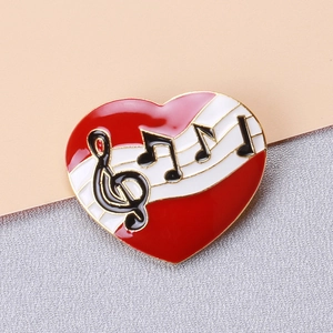 Détail macro d'une broche note de musique en forme de cœur avec émail rouge et blanc sur or