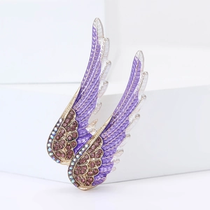 Détail de broche ailes d'ange avec strass violets et plumes en émail doré