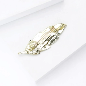 Detail view of the gold feather brooch back showing the secure horizontal metal safety pin