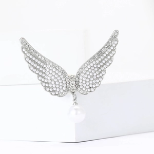 Vue détaillée d'une broche ailes d'ange avec perles et strass sur un support blanc