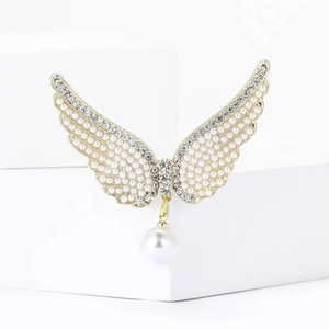 Broche ailes d'ange élégante avec perles et cristaux sur un socle en pierre blanc