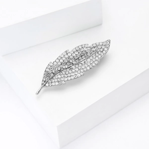 Close-up of elegant silver leaf brooch with sparkling pavé rhinestones on white block
