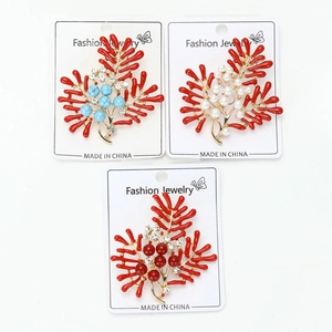 Detail of three coral-shaped brooches with pearls and blue beads on a white card