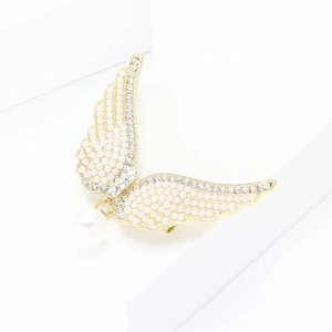 Élégante broche ailes d'ange dorées avec perles et cristaux sur un présentoir blanc