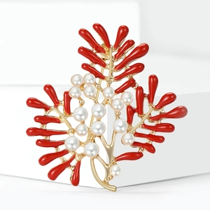 Detail of red enamel coral branch brooch with white pearls on golden metal base