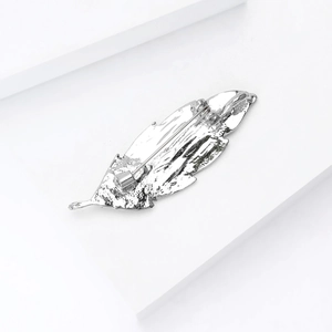 Macro shot of silver feather brooch with metallic texture and secure pin clasp detail