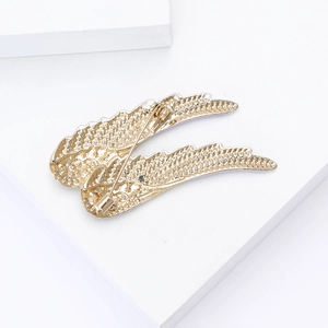 Détail de l'arrière d'une broche en ailes d'ange dorées montrant l'épingle de fixation