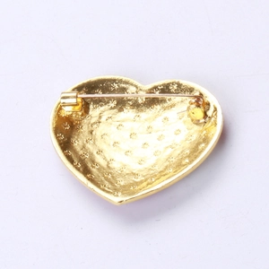 Détail de l'arrière d'une broche cœur montrant l'épingle de sûreté et la texture métal