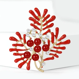 Elegant gold coral brooch with red enamel and pearls on a premium white display stand