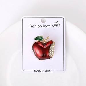 Macro detail of red enamel apple brooch with sparkling crystals on jewelry card