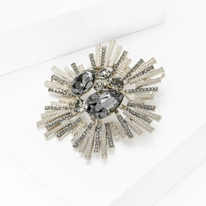 Gros plan détaillé d'une broche baroque argentée avec cristaux gris et rayons scintillants