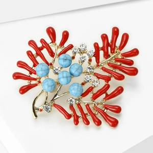 Detail of elegant red coral-inspired brooch with blue turquoise beads and crystals