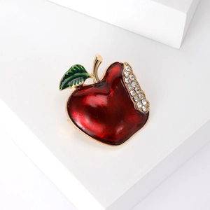 Elegant red apple enamel brooch with sparkling crystals on minimalist white pedestal