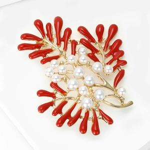 Detail of golden coral brooch with red enamel and multiple white pearls on white background