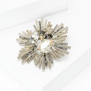 Détail macro d'une broche baroque en cristal avec motif soleil argenté et strass
