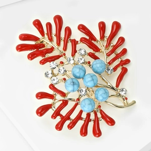 Detail view of red coral brooch with blue stones and crystals on gold finish base