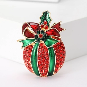 Detailed macro shot of a rhinestone apple brooch with red and green enamel bow on white block