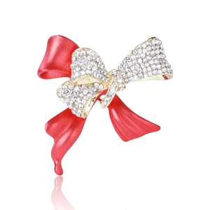 Détail du revêtement en émail rouge et des strass blancs sur la broche nœud chic