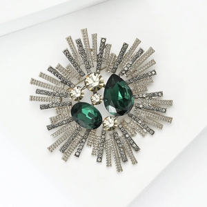 Détail de la broche rétro avec cristaux vert émeraude et zircons sur monture argentée
