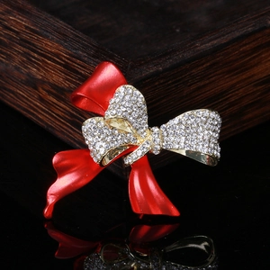 Vue détaillée d'une broche nœud rouge élégante avec des strass étincelants sur doré