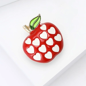 Red enamel apple brooch with white heart patterns and gold-tone stem on white background