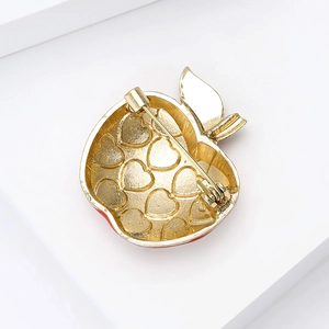 Golden alloy apple brooch with heart embossed back and red enamel detail side view