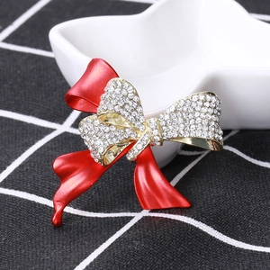 Détail de la broche nœud rouge avec base dorée et strass brillants pour manteaux