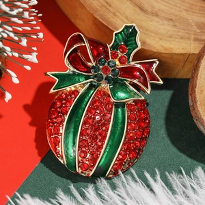 Sparkling Christmas ball brooch with red and green rhinestones on festive background