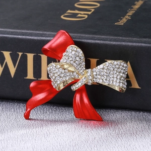 Détail d'une broche nœud en émail rouge avec strass blancs étincelants sur doré
