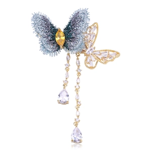 Détail de la broche papillon en tissu brodé avec pompons en zircon et fini doré