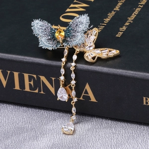 Détail de la broche papillon brodée avec zircons et glands de chaîne dorée