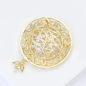 Vue détaillée d'une broche ajourée dorée de style français avec zircons sur fond blanc