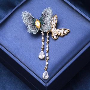 Broche papillon élégante avec broderie grise, zircons et pampilles dorées fines