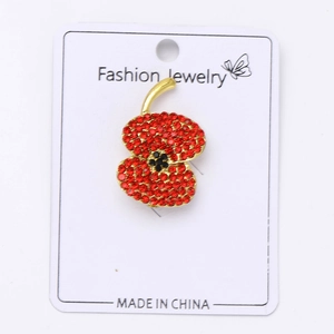 Détail d'une broche coquelicot en strass rouges sur base en alliage doré chic