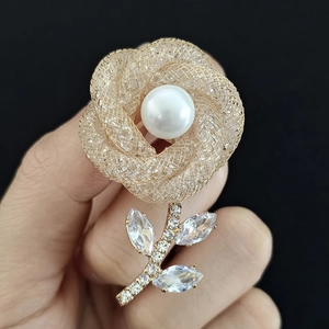 Détail macro de la broche fleur en perle avec pétales en maille dorée et cristaux brillants